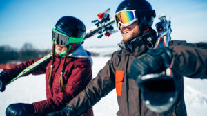 Male and female skiers poses with skis and poles